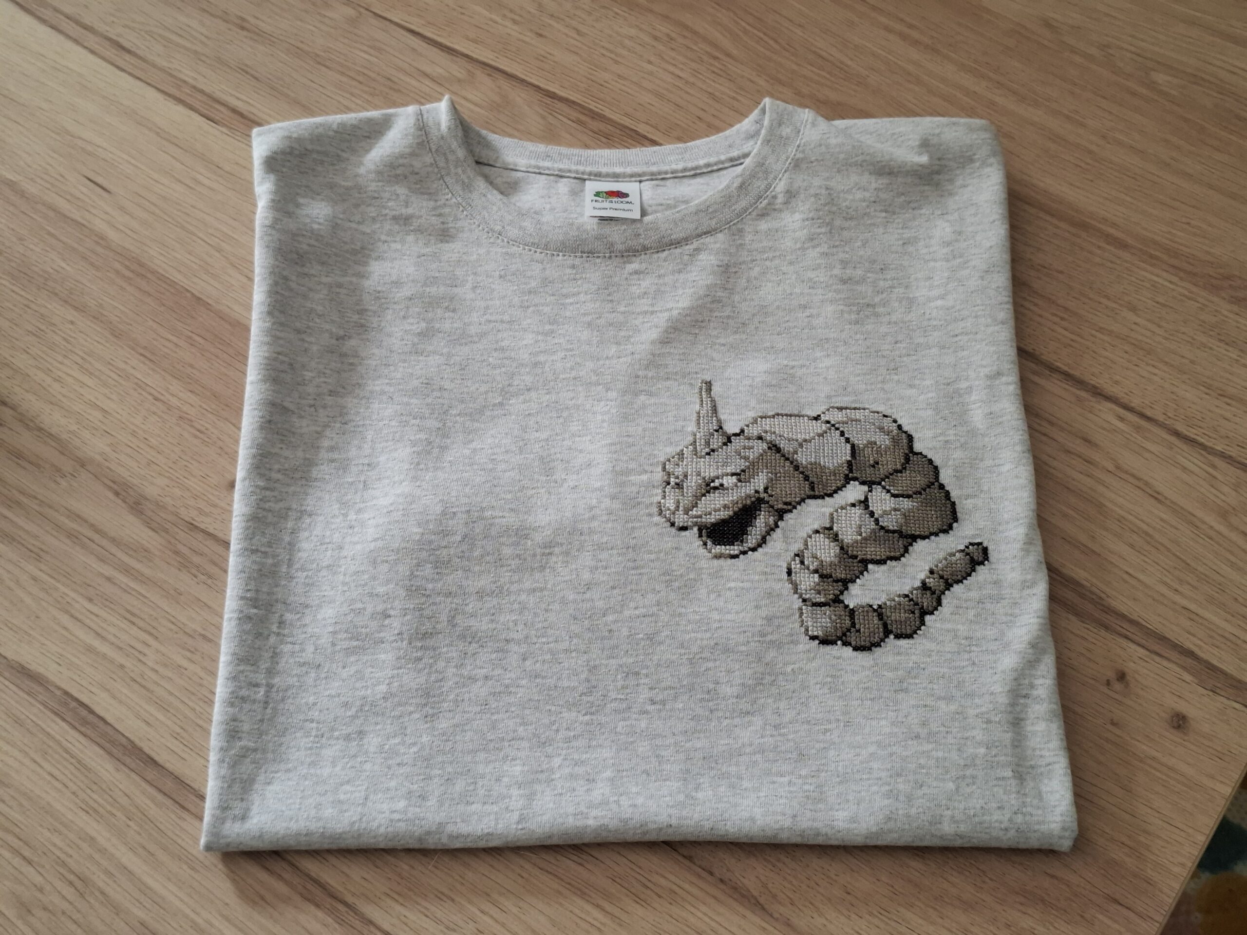 Plan serré sur le t-shirt. T-shirt onix plié, posé sur une table en bois.